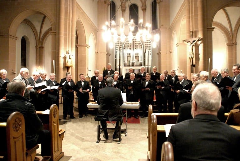 This shows older men singing in a choir