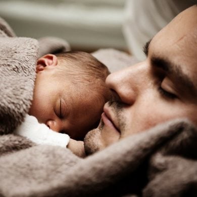 This shows a dad holding his sleeping baby