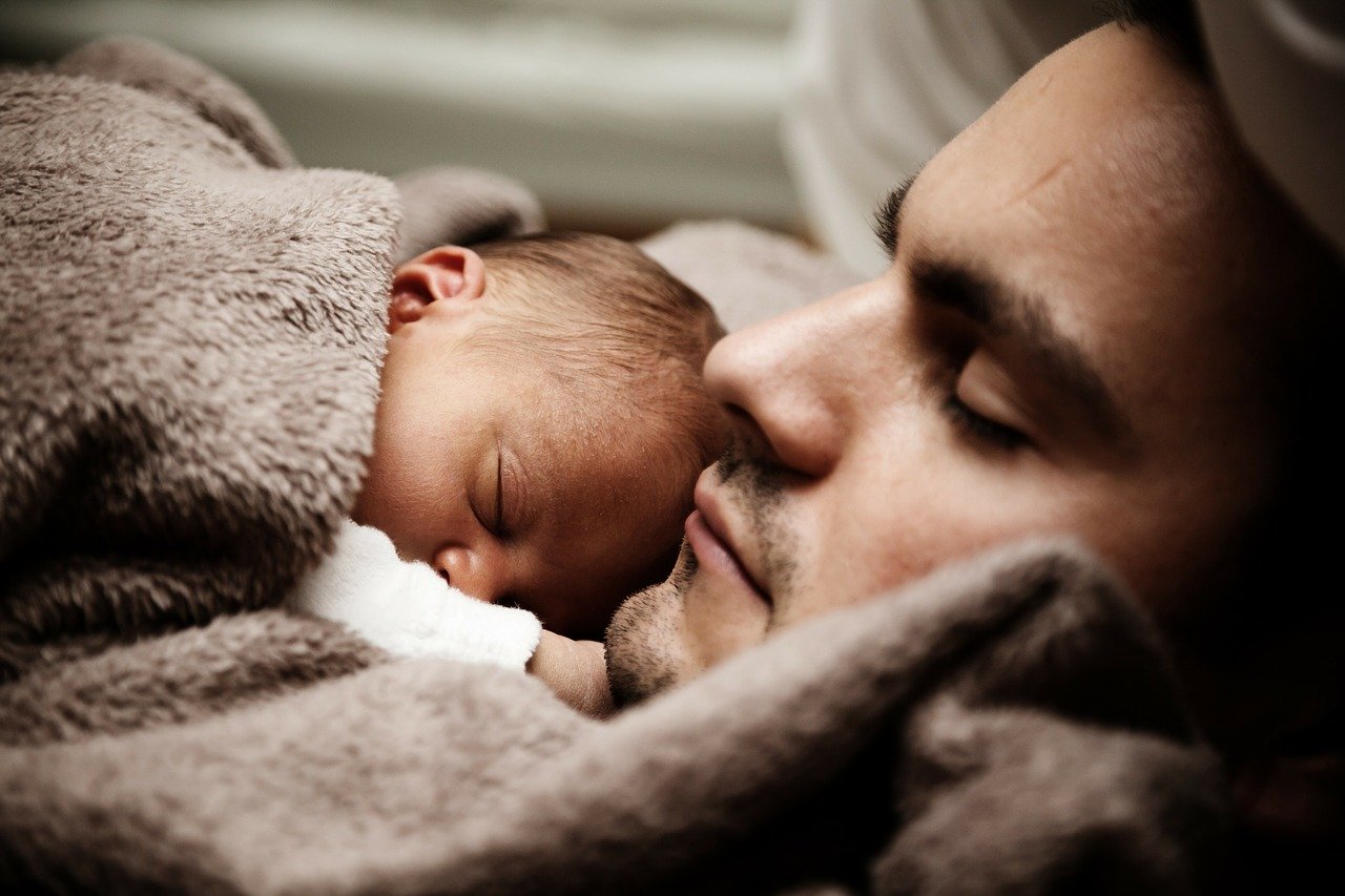 This shows a dad holding his sleeping baby