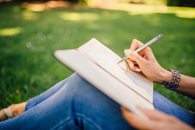 This shows a woman writing in what looks like a journal