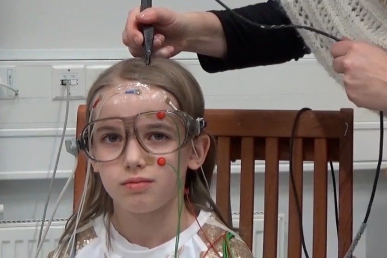 This shows a little girl with an EEG cap on