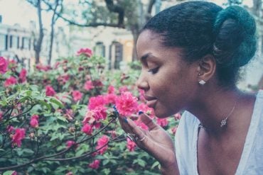 This shows a woman smelling flowers in a garden