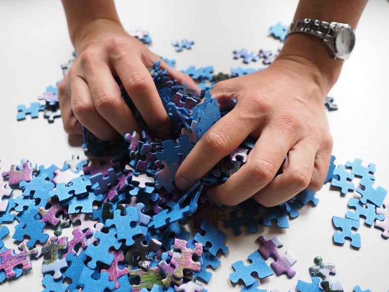 This shows a woman's hands sorting through jigsaw pieces