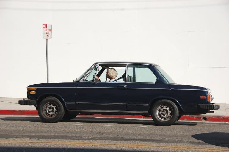 This shows an older lady driving a vintage car