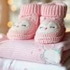 This shows pink baby booties and pink baby blankets