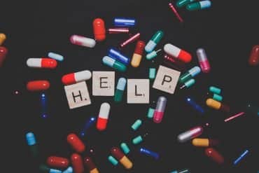 This shows different colored pills and scrabble tiles spelling out "help"