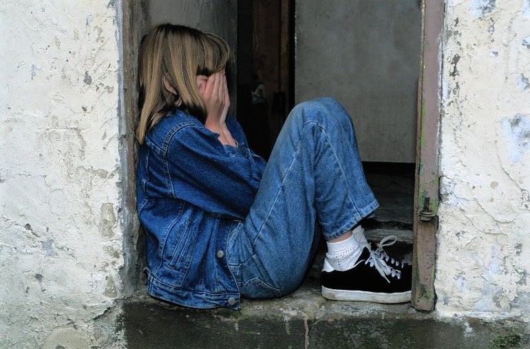 This shows a young girl crying in a doorway