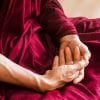 This shows an older person's hands crossed in meditation