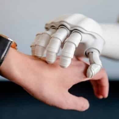 This shows a robot hand resting on top of a person's hand