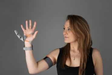 This shows the researcher with the thumb prosthetic on her hand