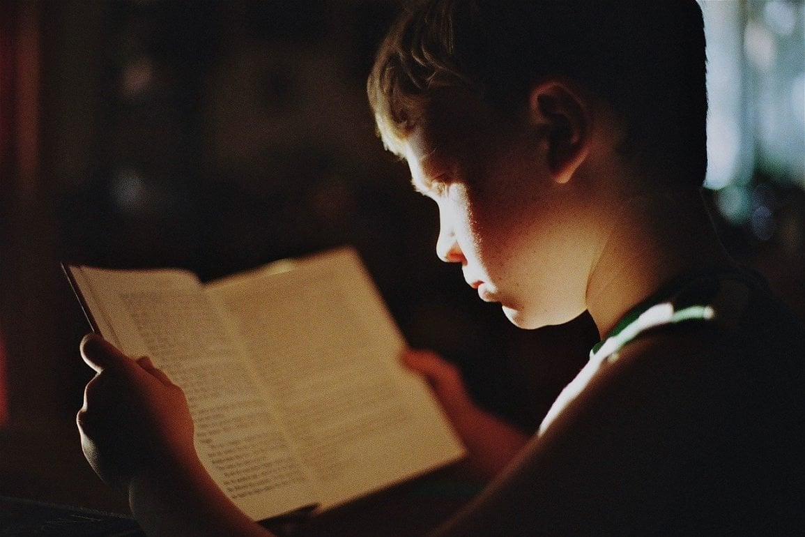 This shows a little boy reading a book