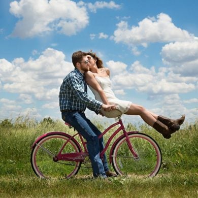This shows a happy couple riding a bicycle