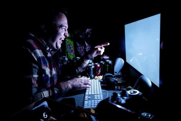 This shows a man laughing at a computer screen