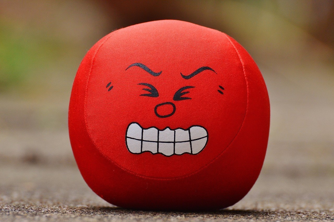 This shows a red ball with a sour looking face painted on it