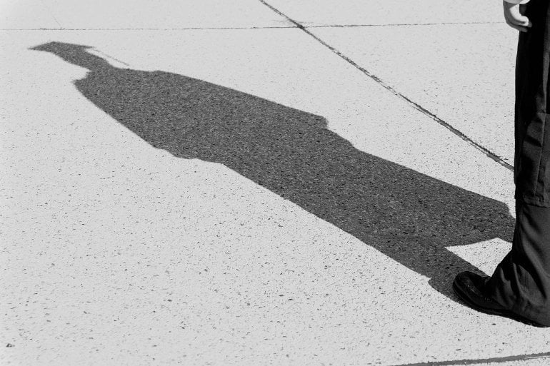 This shows the shadow of a person in a graduation cap and gown