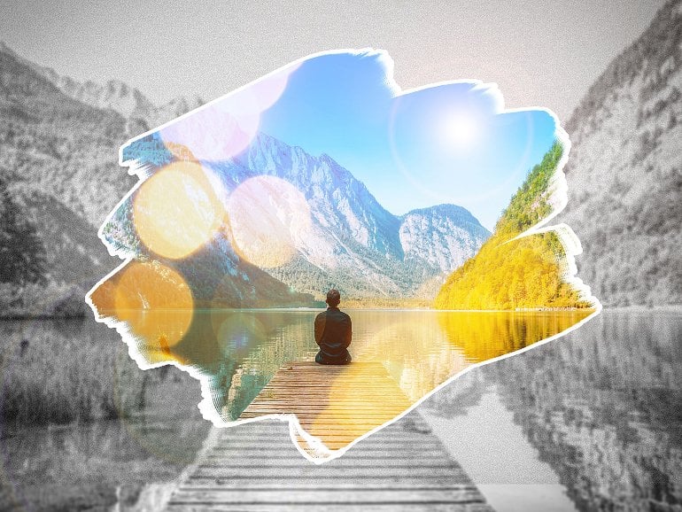 This shows a person sitting on a dock looking at a mountain range