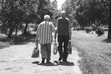This shows an older couple walking with shopping bags