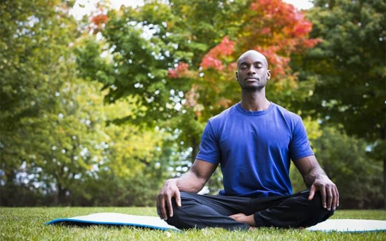 This shows a man meditating in a park