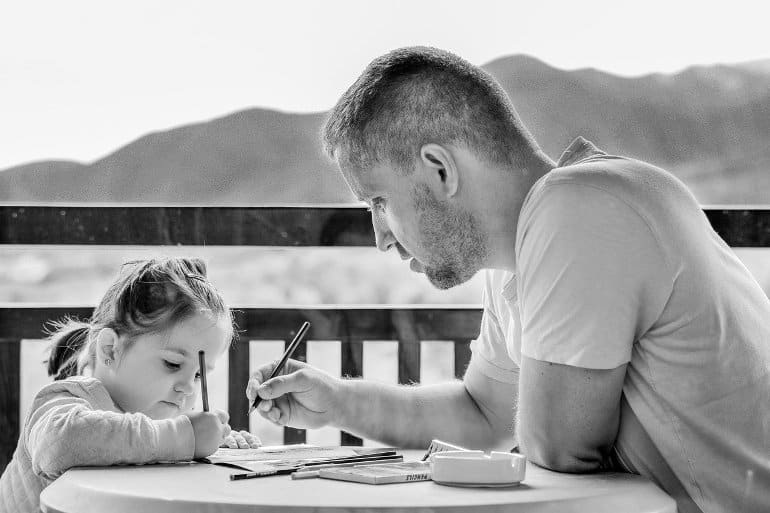 This shows a dad doing homework with his little girl