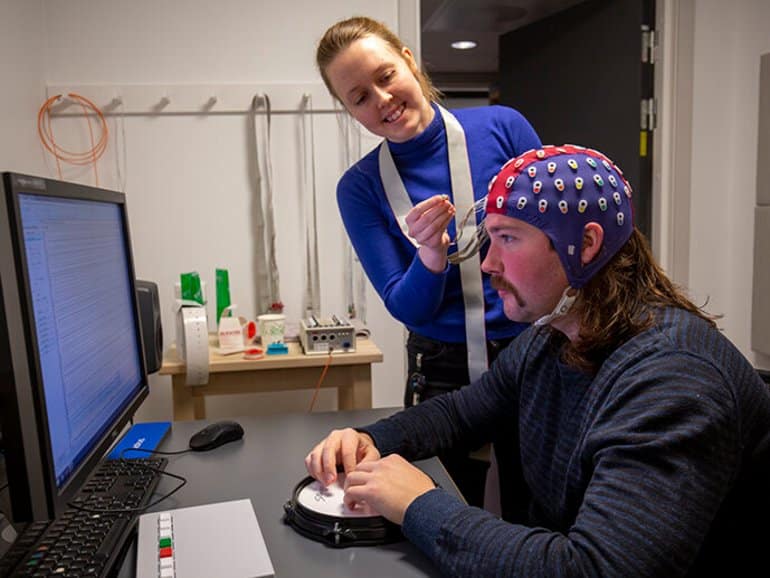 This shows the researcher putting an EEG cap on a study participant