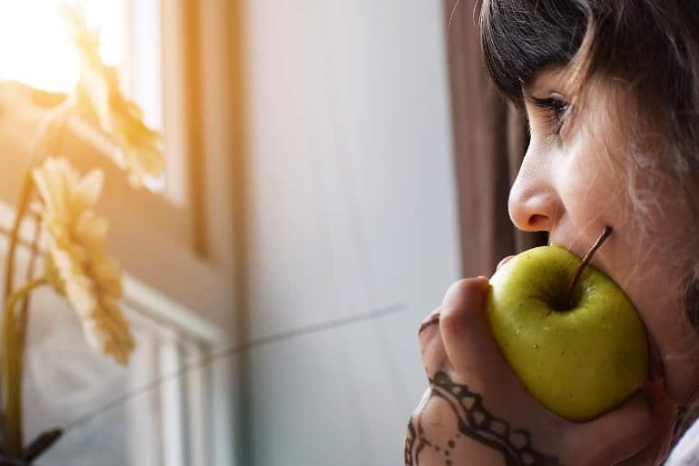 This shows a little girl eating an apple