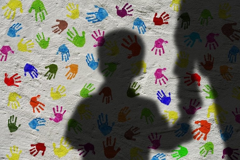 Isso mostra a sombra de uma criança e uma parede coberta com impressões manuais multicoloridas