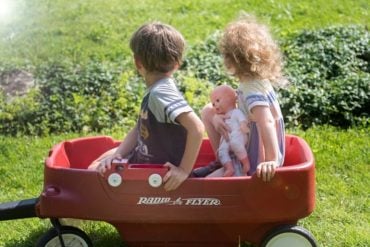 This shows children playing in a red pull wagon