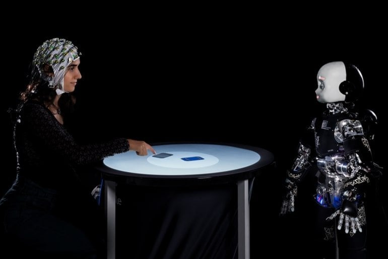 Isso mostra uma mulher jogando cartas com um robô