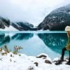 This shows a woman standing next to a lake on a snowy day