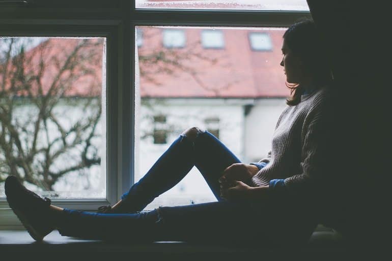 This shows a woman looking out of a window