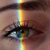 This shows a woman's eye with a rainbow light beam over it
