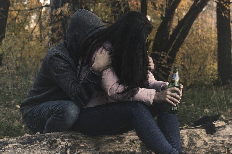 This shows a young woman looking depressed with a drink in her hand