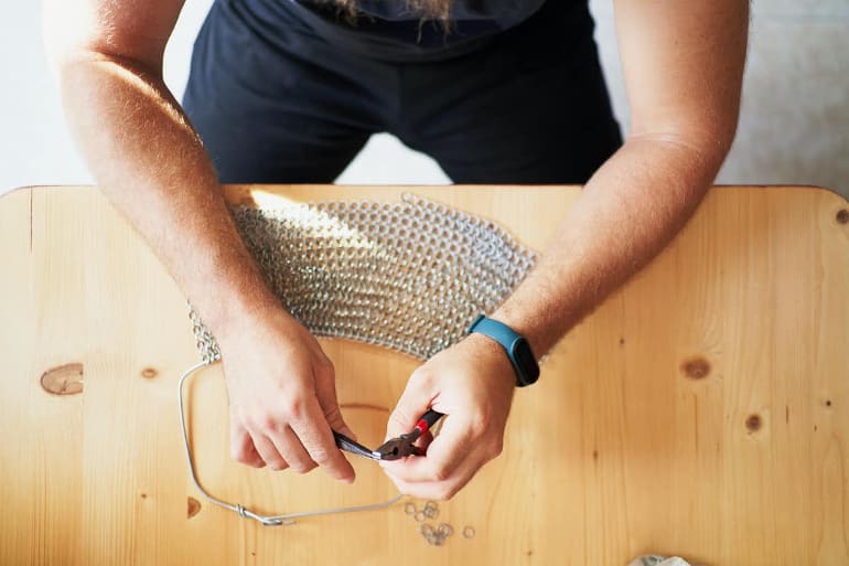 This shows a person making a metal bag, using hand tools