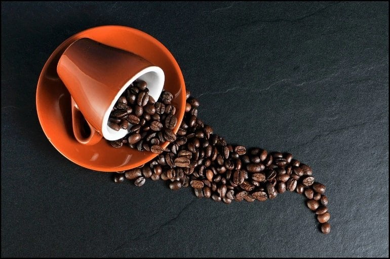 This shows a tipped cup and coffee beans