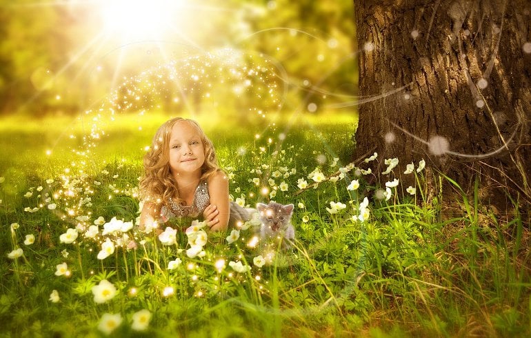 This shows a young girl sitting under a tree in the sunshine