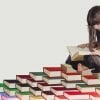 It shows a little girl reading on a pile of books