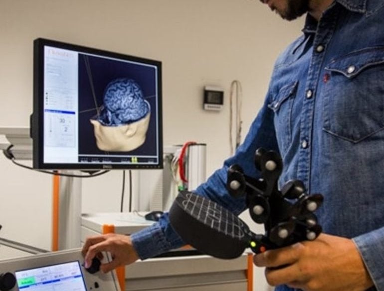 This shows the researcher holding a brain stimulation device
