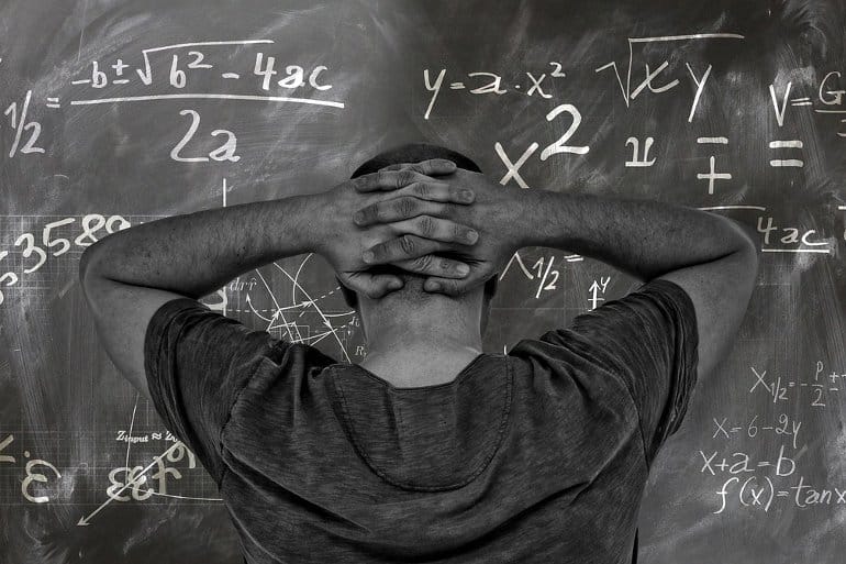 This shows a man standing at a blackboard covered in math equations