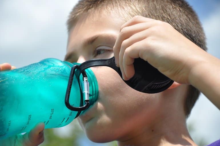 This shows a boy drinking from a water bottle