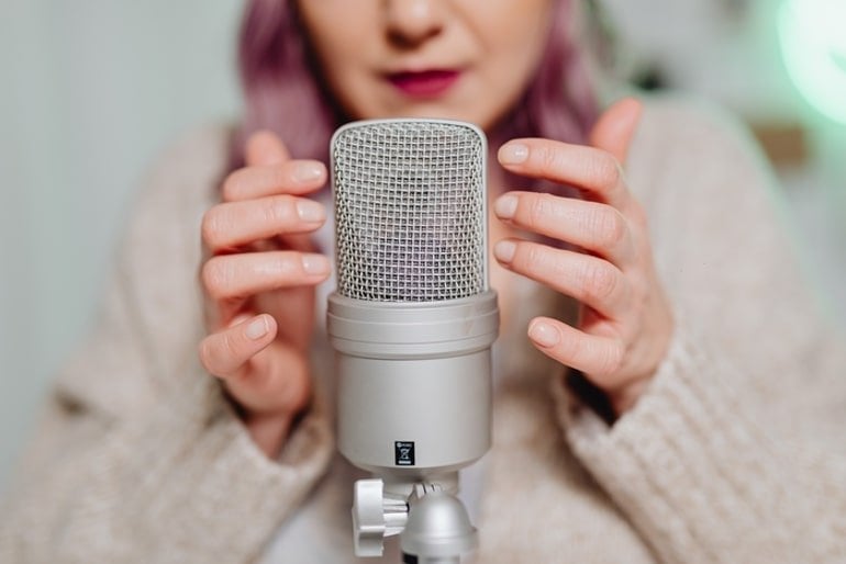 This shows a woman gently touching a microphone