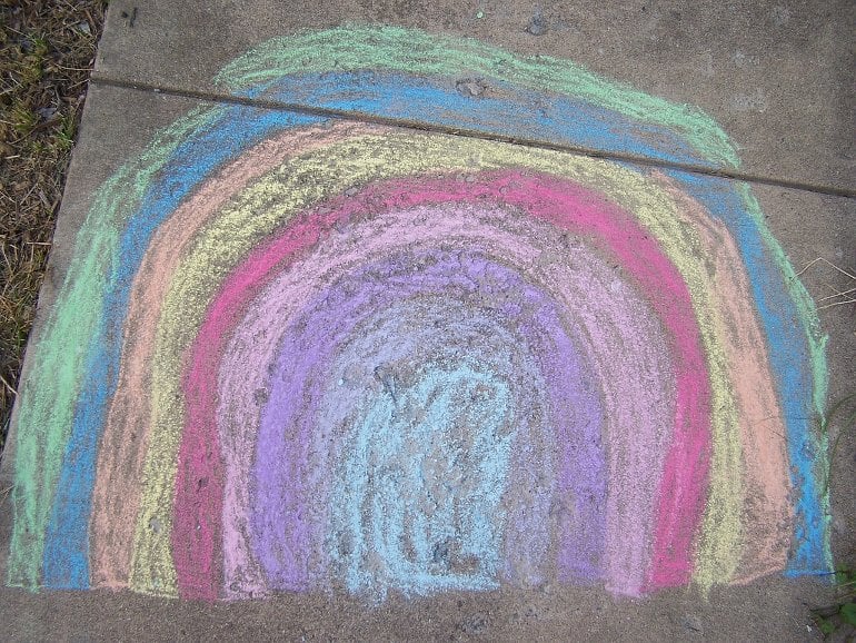 This shows a chalk drawing of a rainbow on a sidewalk