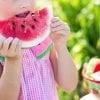 This shows a little girl eating a watermelon slice