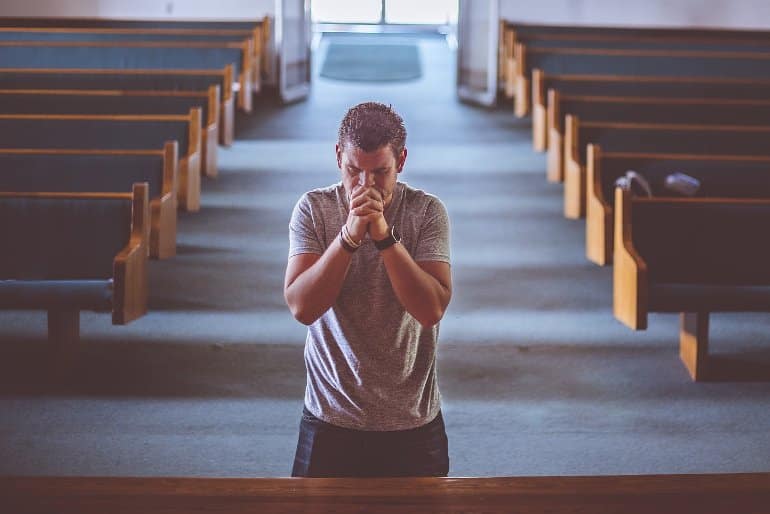 This shows a man praying in church