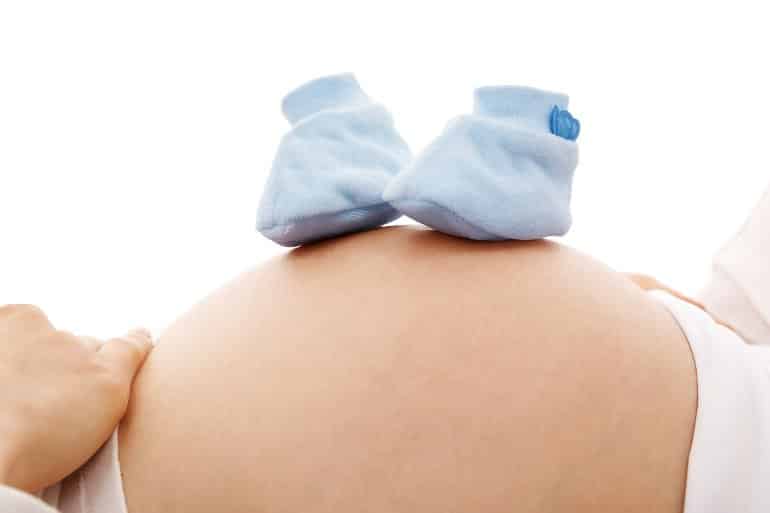 This shows a pregnant woman's body and a pair of blue baby booties