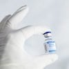 This shows a gloved hand holding a COVID vaccine vial