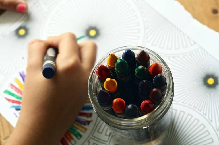 This shows a child coloring with crayons