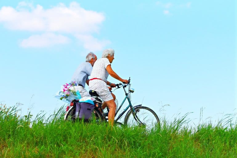 This shows an older couple riding bicycles