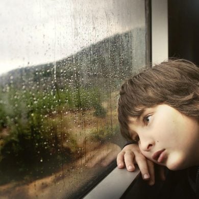 This shows a sad boy looking out a window