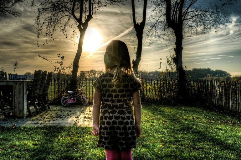 This shows a young girl standing in a garden