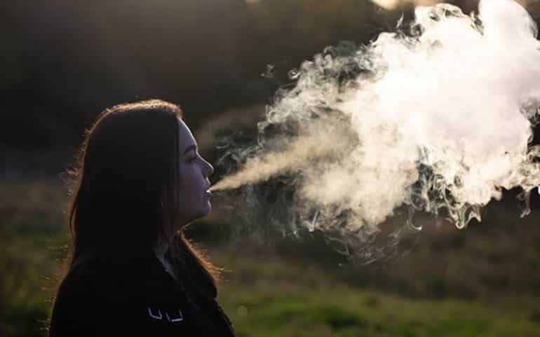 This shows a woman exhaling vape smoke